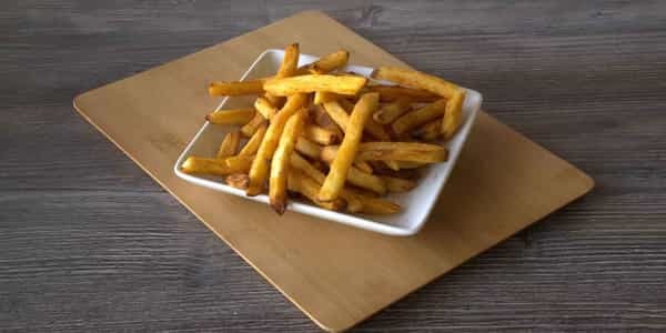 Plate of golden, seasoned fries on a wooden board.