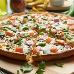 Vegetarian pizza with mushrooms, peppers, tomatoes, and red onion on a wooden board.